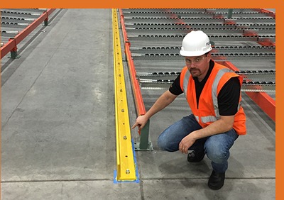 Man in a hard hat and safety vest crouched on warehouse floor