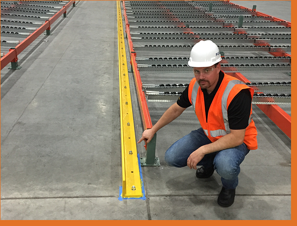 Man in a hard hat and safety vest crouched on warehouse floor