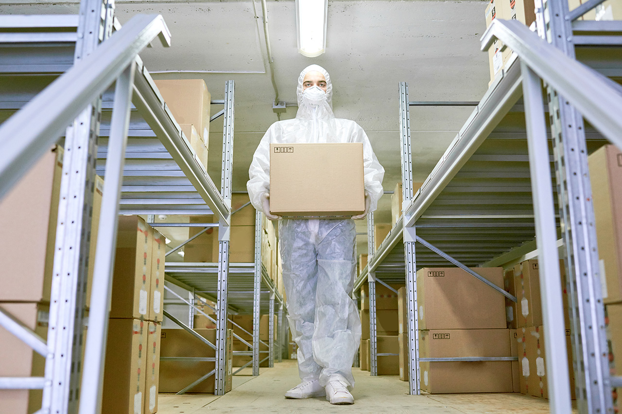 worker in protective gear carrying box