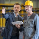 businessman talking to working man in factory