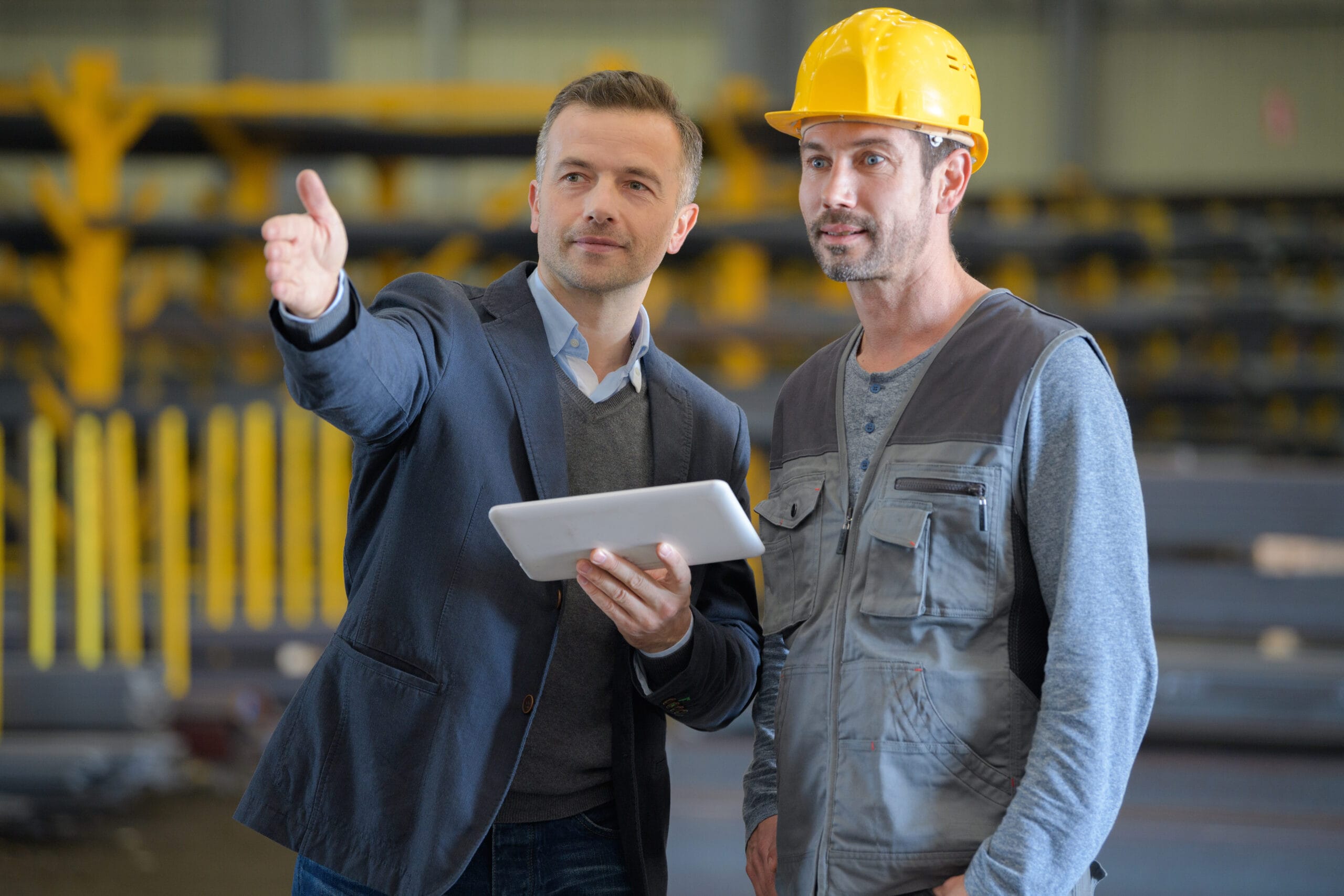 businessman talking to working man in factory