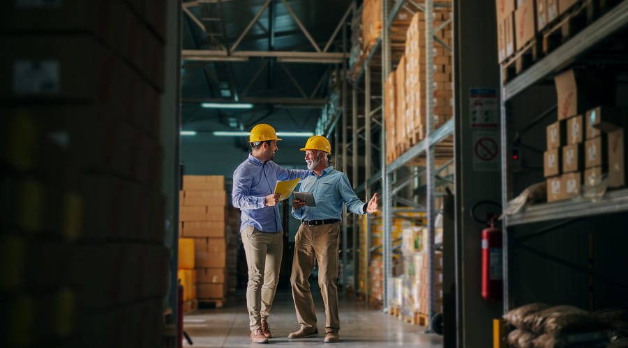 two men wearing hard hats in a warehouse